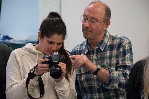 Woman student being taught how to use her camera by a male tutor
